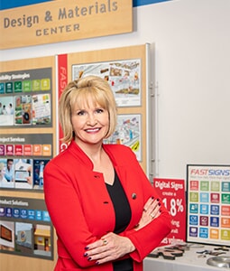 Catherine Monson poses next to FASTSIGNS Design and materials center